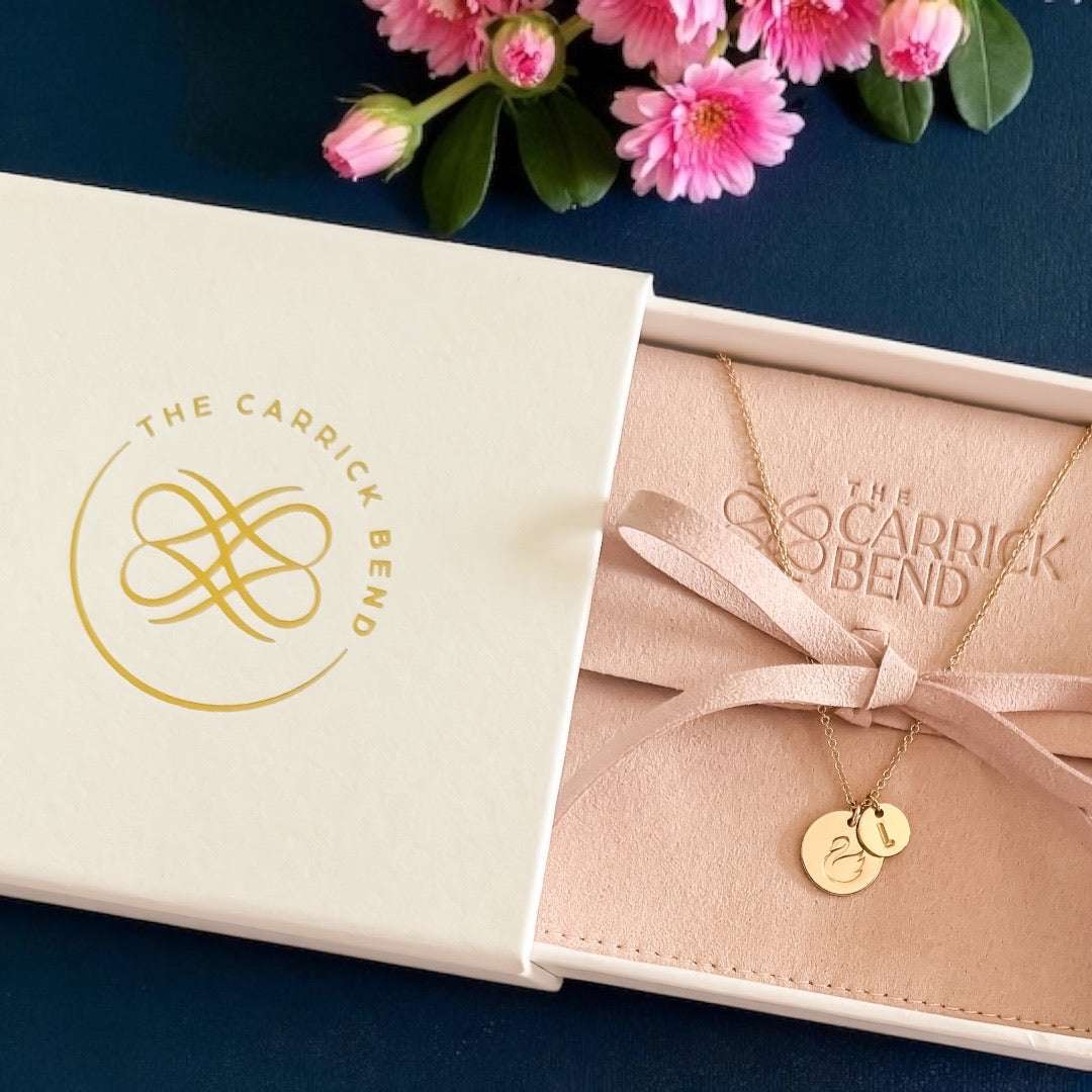 Stamped Story Necklace in gold-tone metal with a fine chain and two small round charms, presented in a blush pouch