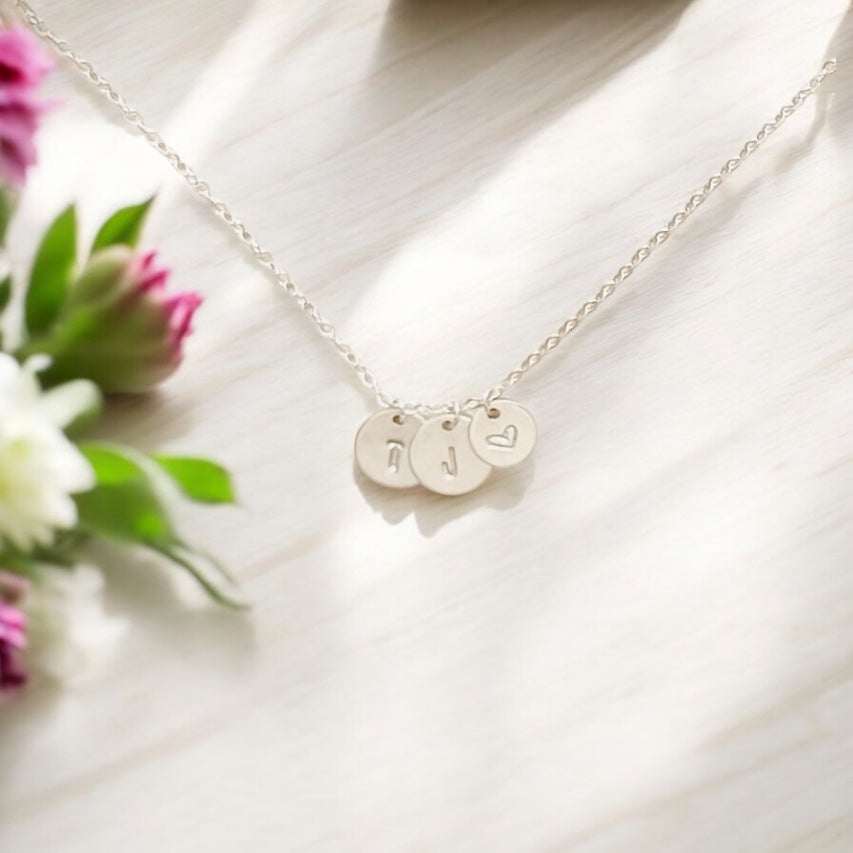 Stamped Story Necklace in silver with three round hand-stamped charms, including initials and a heart design, on a fine chain